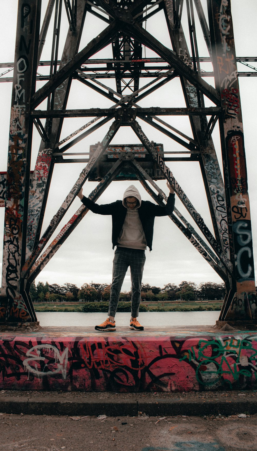 茶色の木製の橋の上に立つ黒いジャケットの男