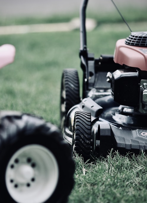 black and red ride on lawn mower on green grass field during daytime