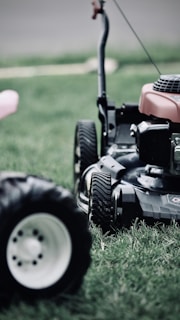 black and red ride on lawn mower on green grass field during daytime