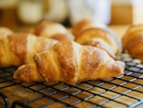 Close-up of freshly baked golden croissants on a rustic wooden table.