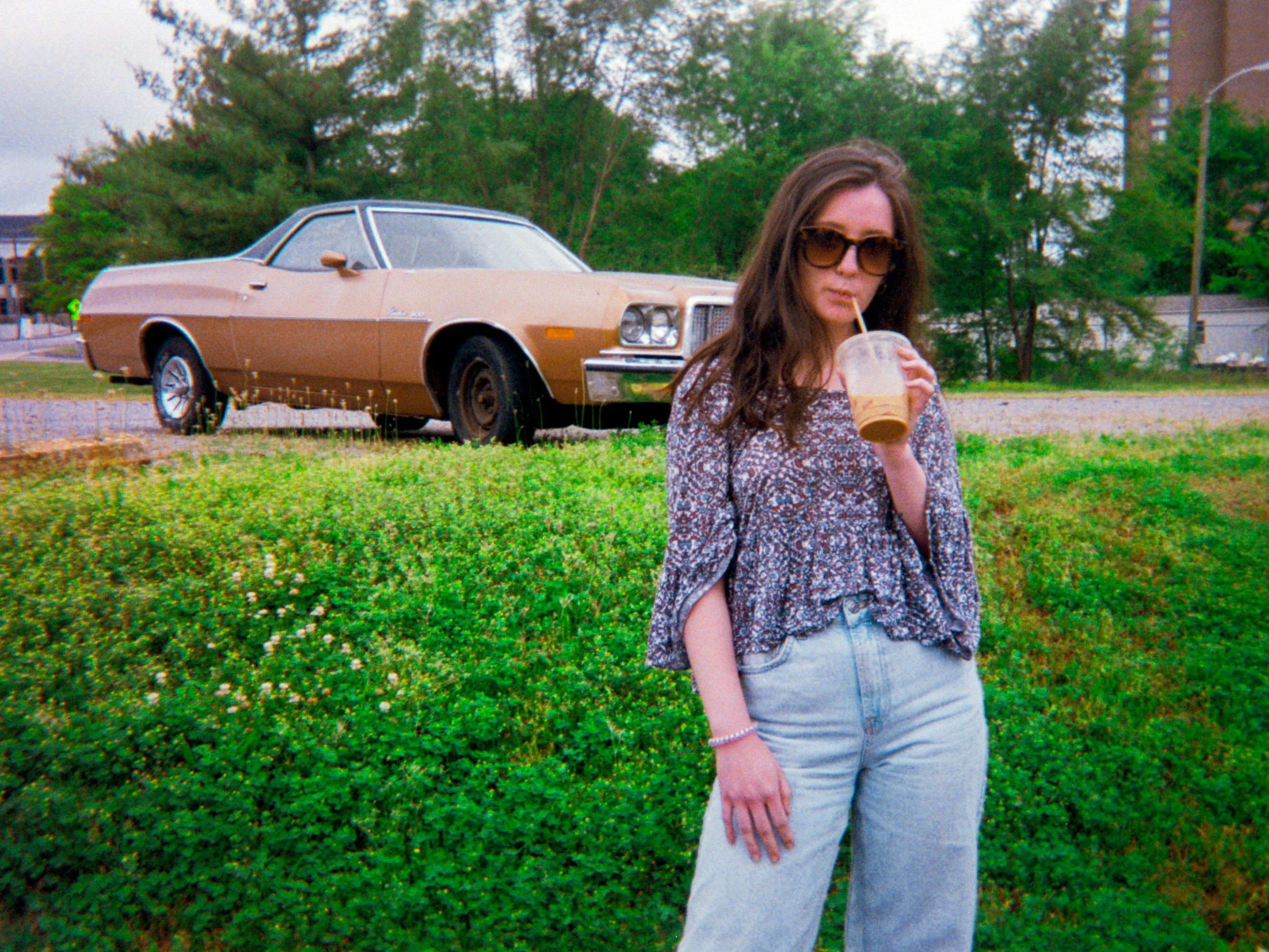 woman in blue and white floral blouse and gray pants holding white ceramic mug