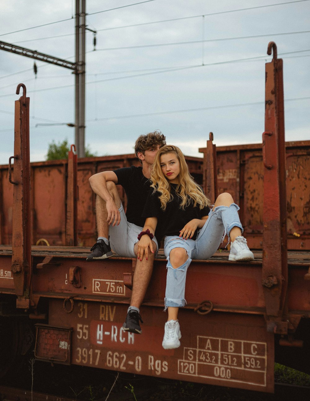 woman in black tank top and blue denim shorts sitting on brown wooden bench during daytime