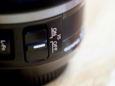 Close-up view of a camera lens with visible switches labeled L-Fn and IS, along with an IS 'ON' and 'OFF' switch. The image captures the details of the lens’s surface and control elements.