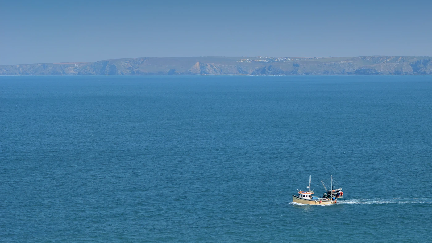 White commercial fishing boat on bright blue water in daylight, representing a successful return to work after a maritime claim