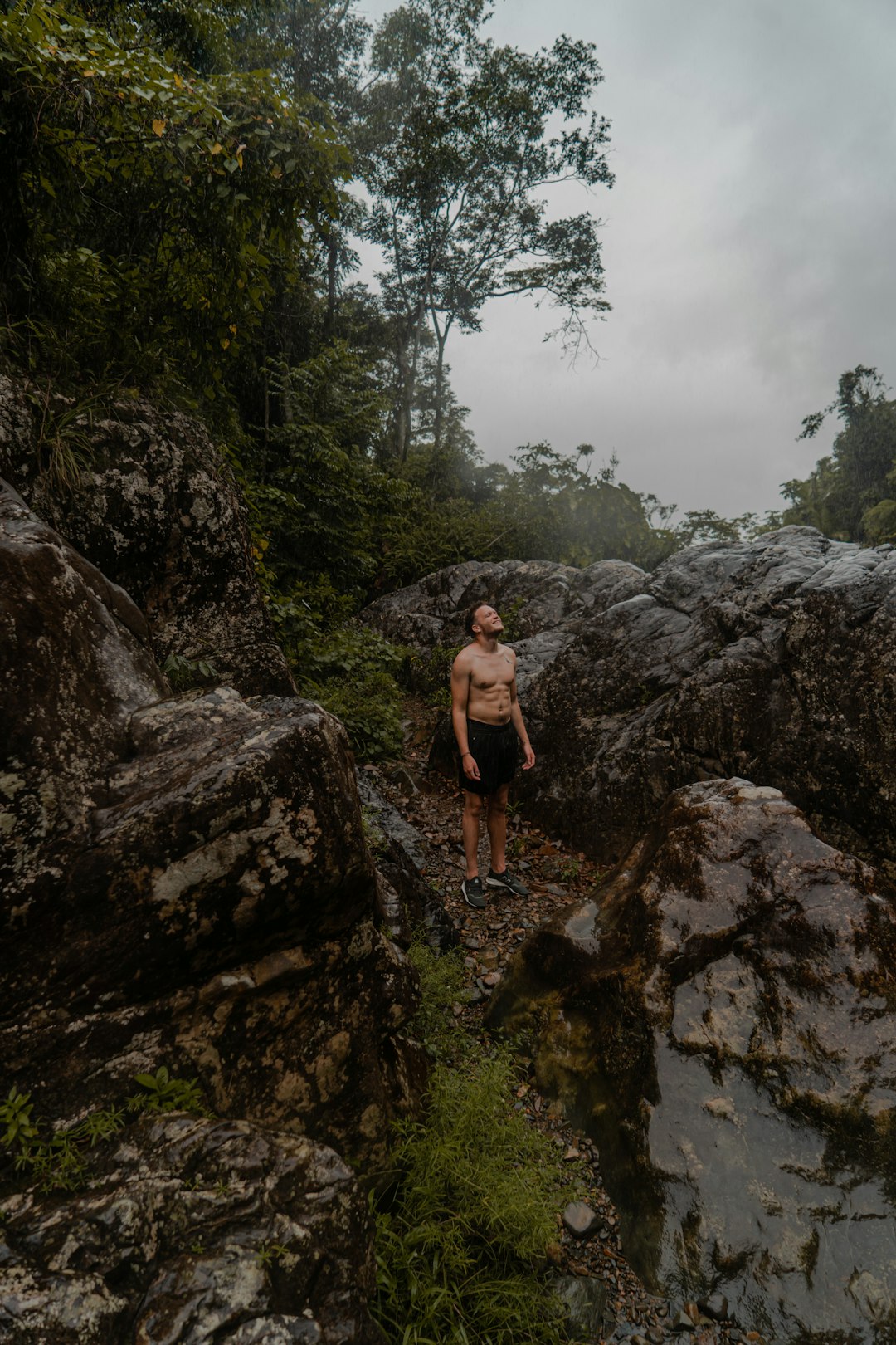 woman in black tank top and black shorts standing on rocky mountain during daytime