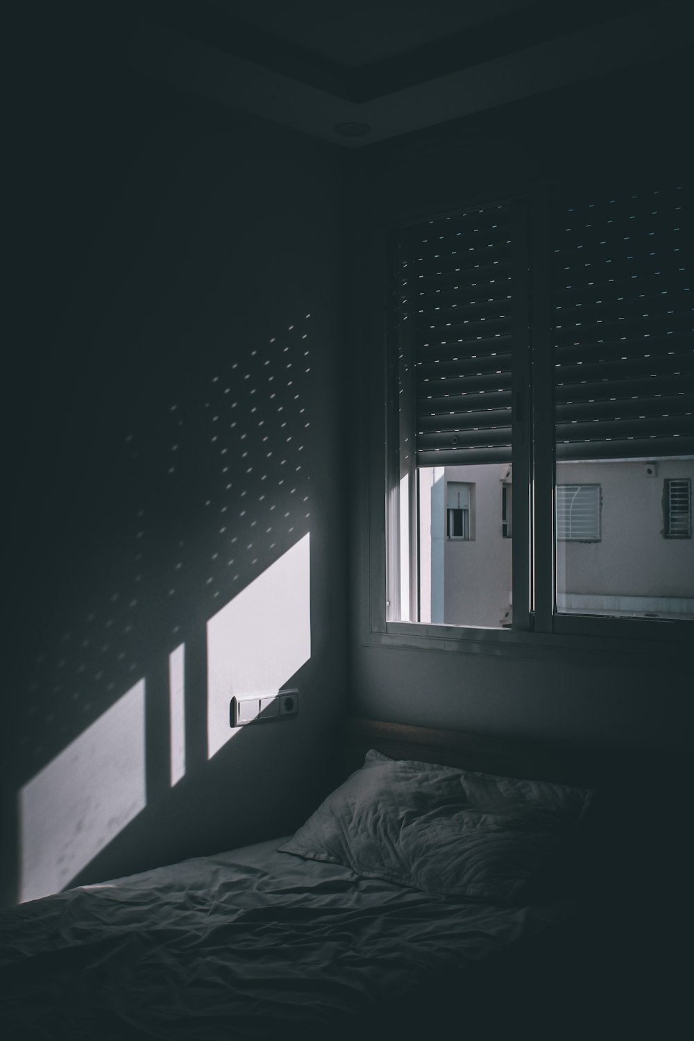 窓の近くのベッドのグレースケール写真