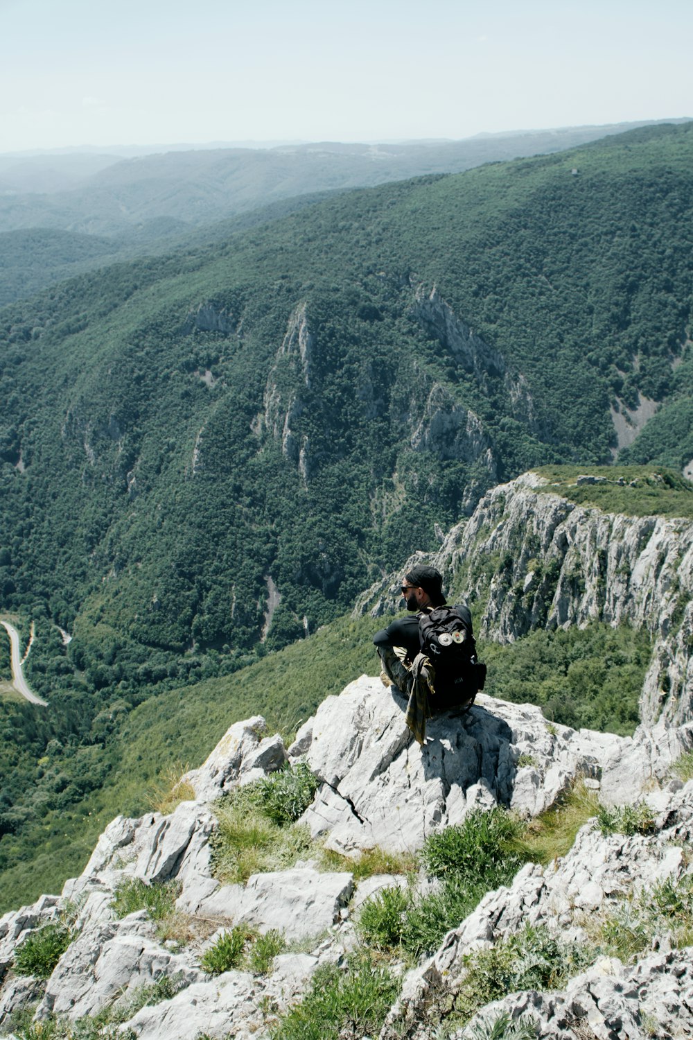 man in black jacket sitting on rock mountain during daytime