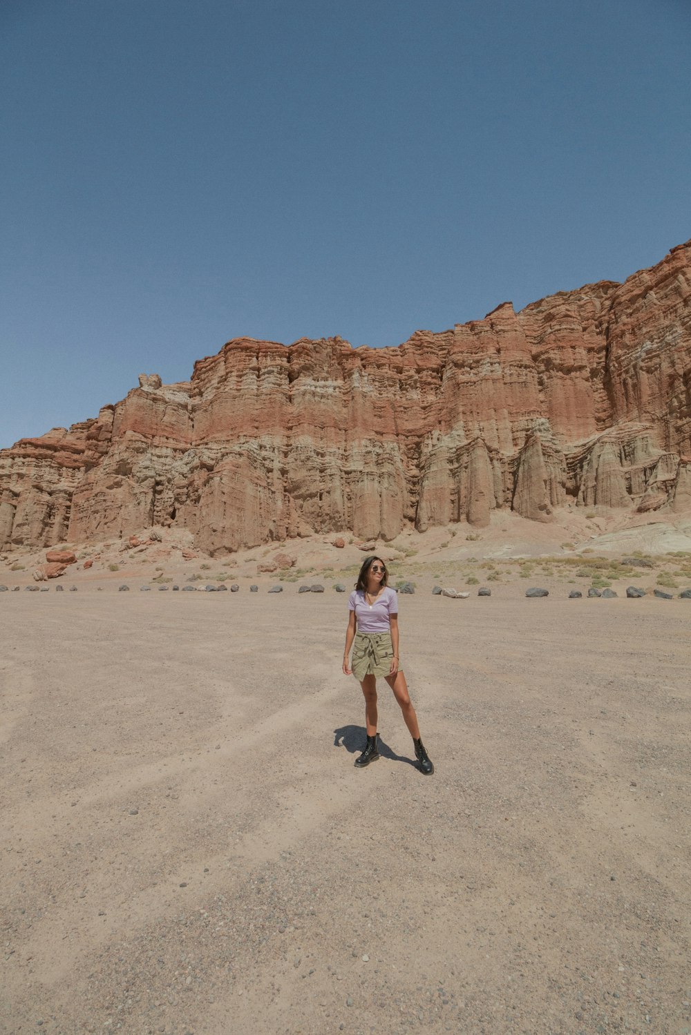 woman in white tank top and black shorts standing on brown sand during daytime