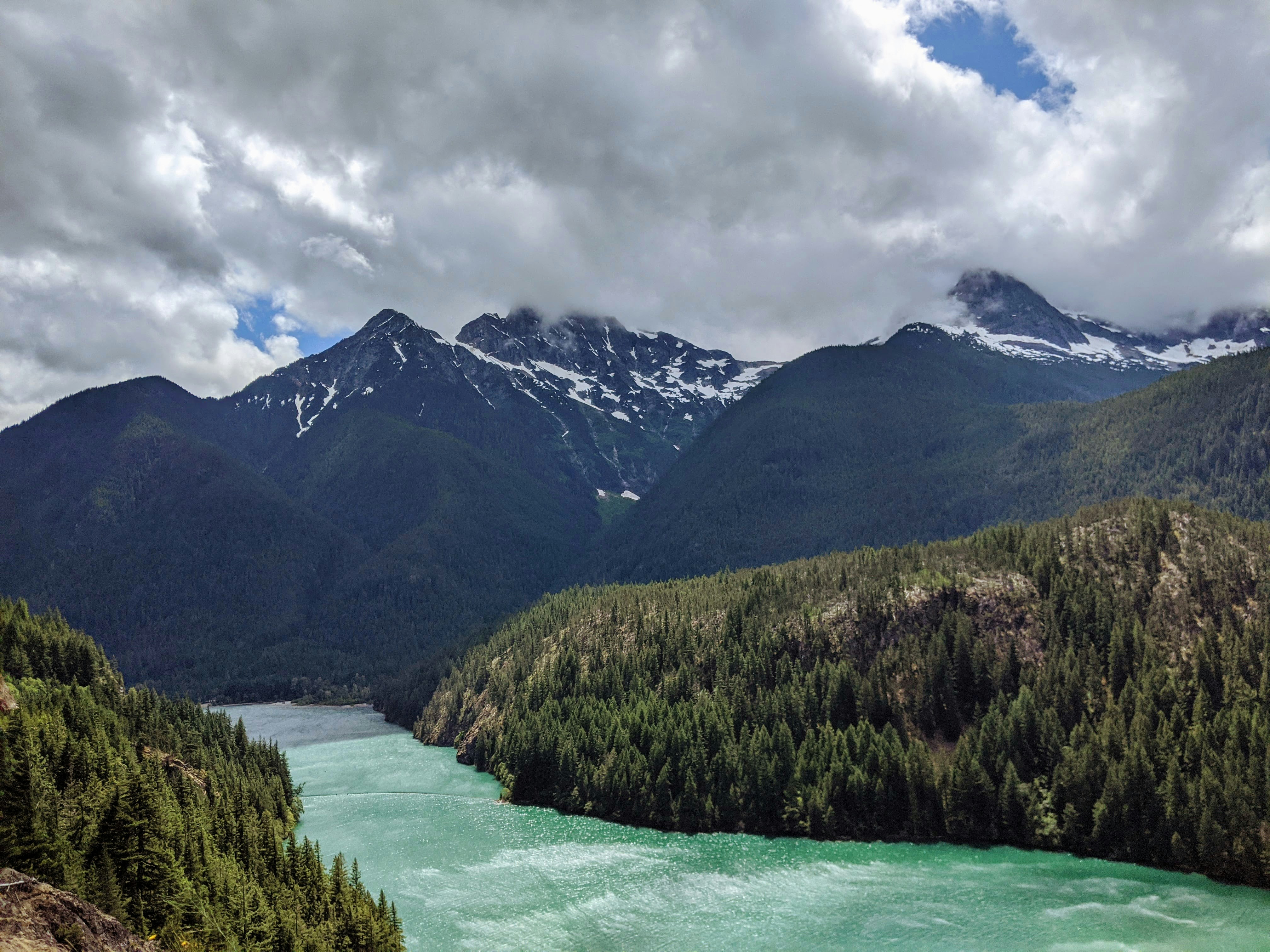green and brown mountains near body of water under white clouds during daytime