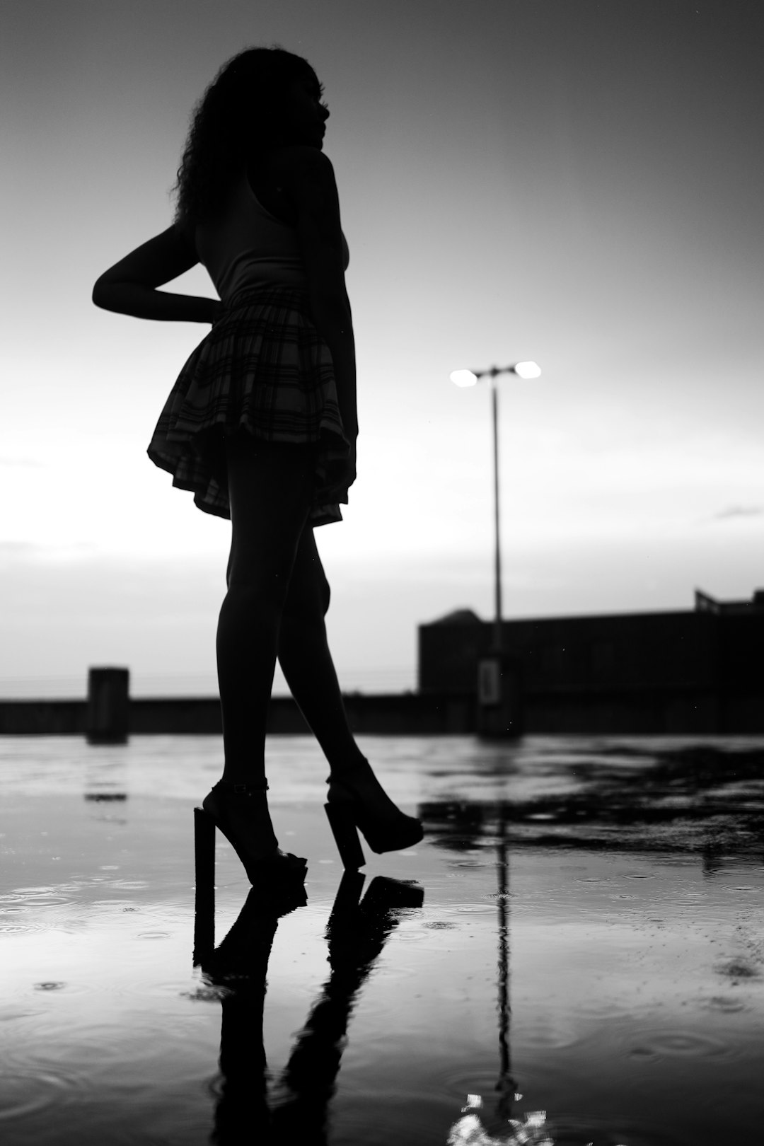 woman in black and white plaid dress shirt and black pants walking on wet ground
