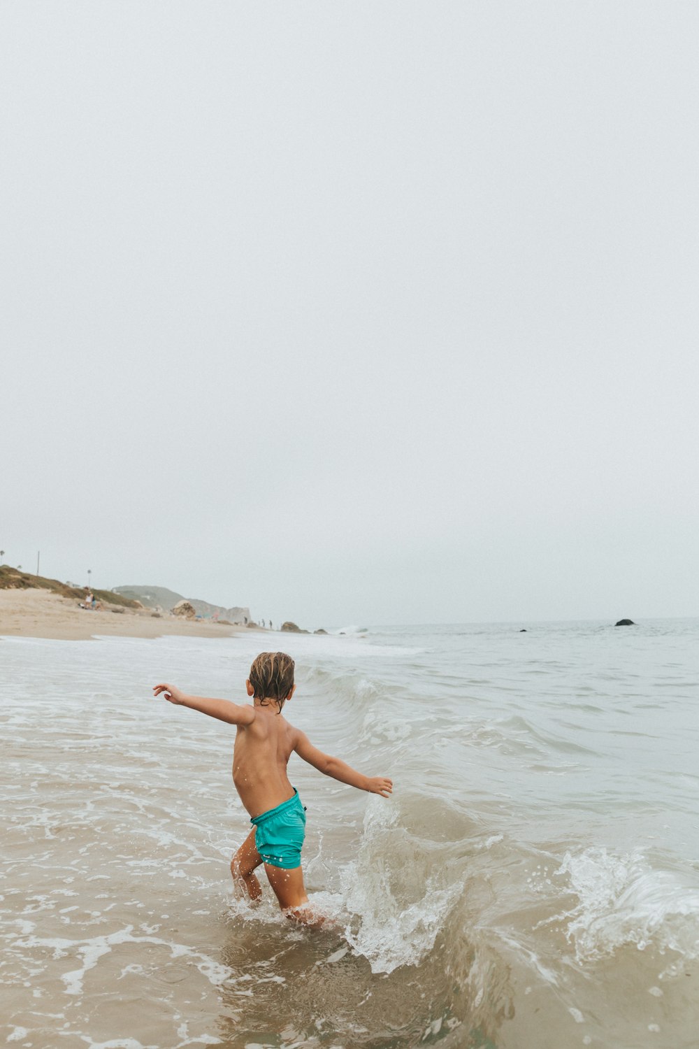 Mädchen in blauen Shorts läuft tagsüber am Strand