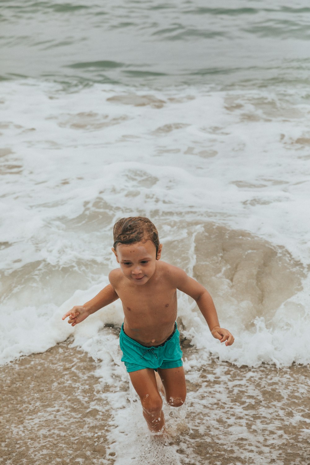 boy in green shorts standing on beach during daytime