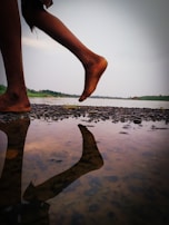 Pilgrims walking barefoot along the riverbank, their reflections shimmering in the water.