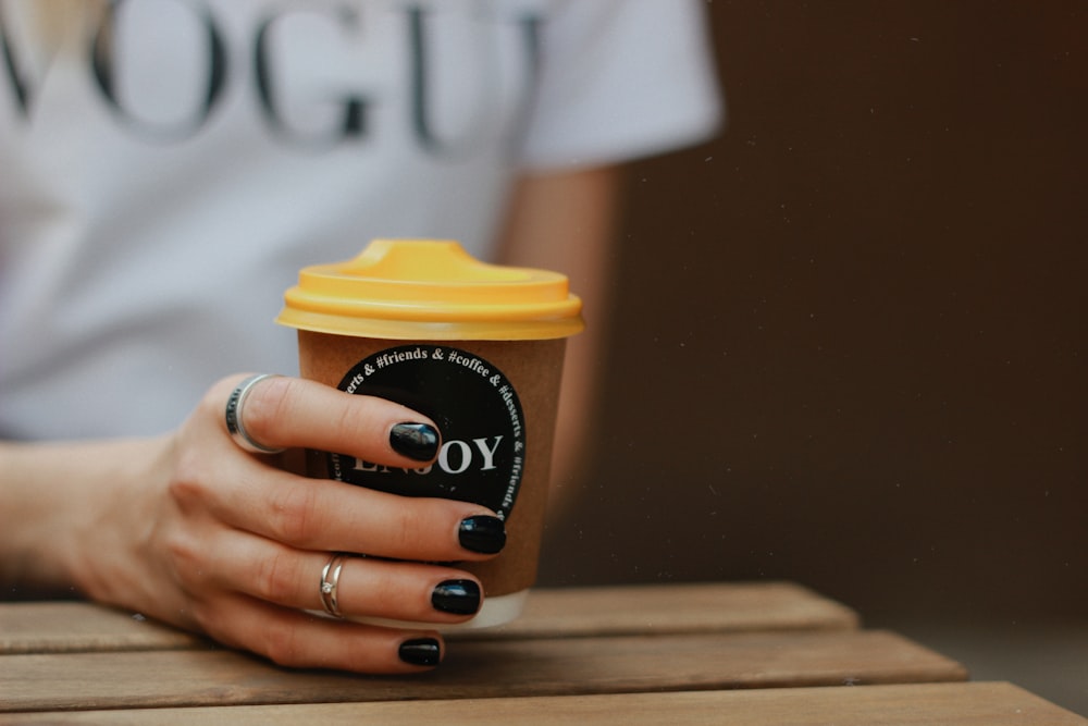 person holding white and yellow coffee cup