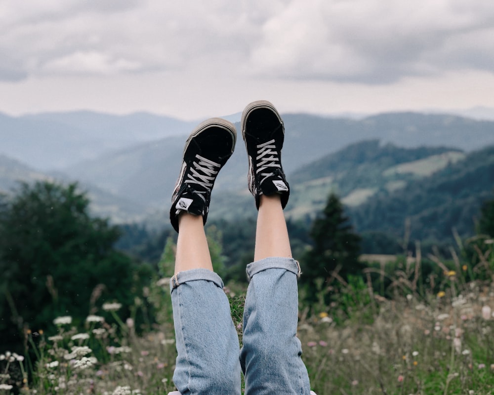 person in blue denim jeans and black and white sneakers