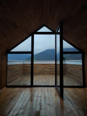 Sunlit triple-bed room with wooden furniture and mountain views through the window.
