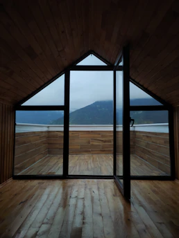 Sunlit triple-bed room with wooden furniture and mountain views through the window.