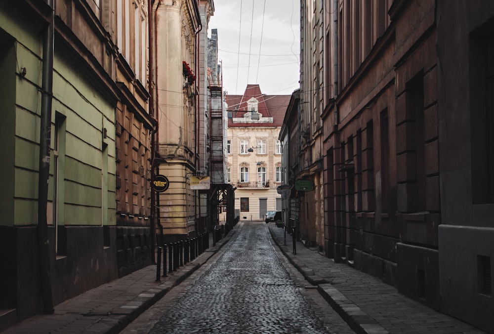 empty street between brown concrete buildings during daytime