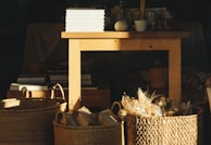A rustic wooden table with a Bellas Cestas basket surrounded by morning sunlight.