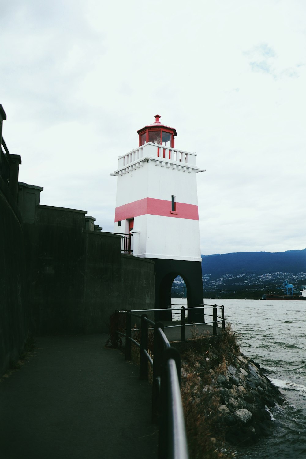 red and white concrete lighthouse near body of water during daytime