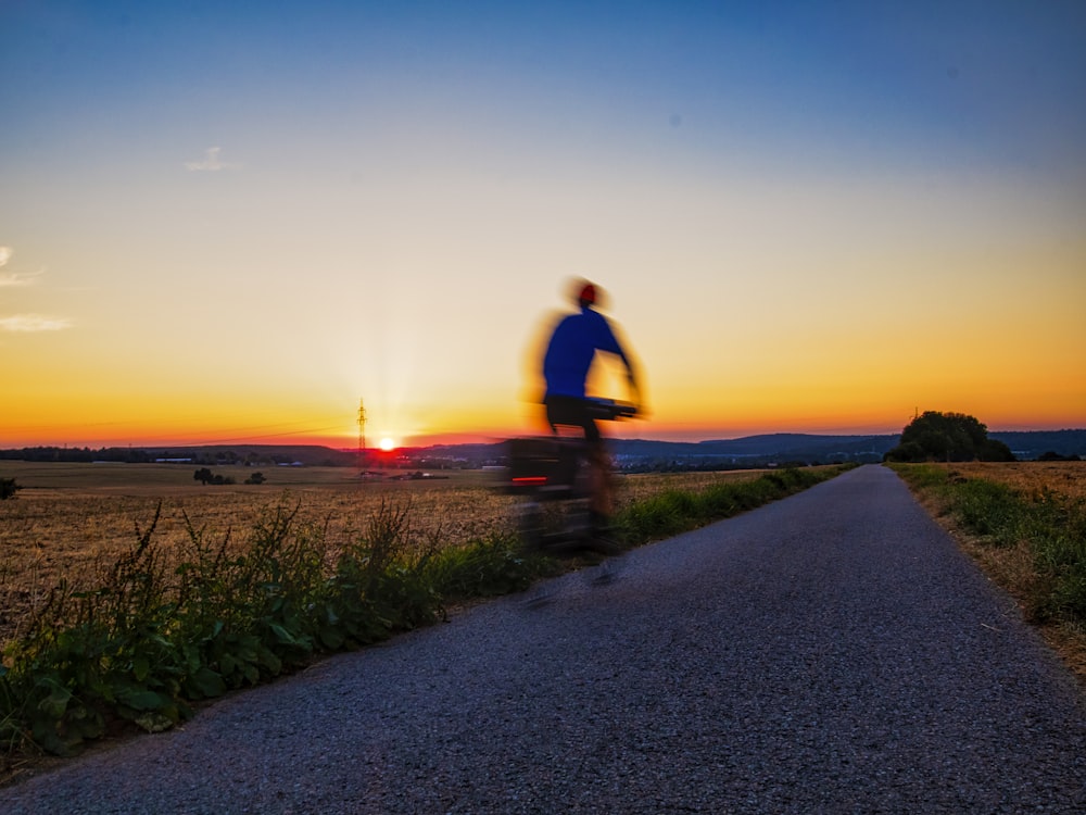 man in black t-shirt and black pants walking on gray concrete road during sunset