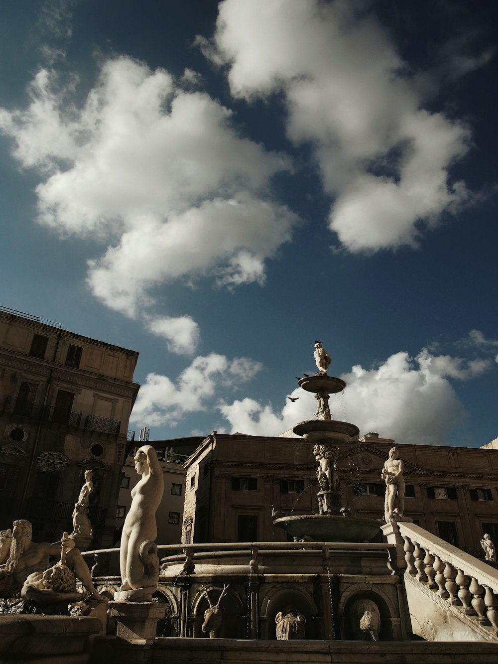 statue of people under blue sky and white clouds during daytime