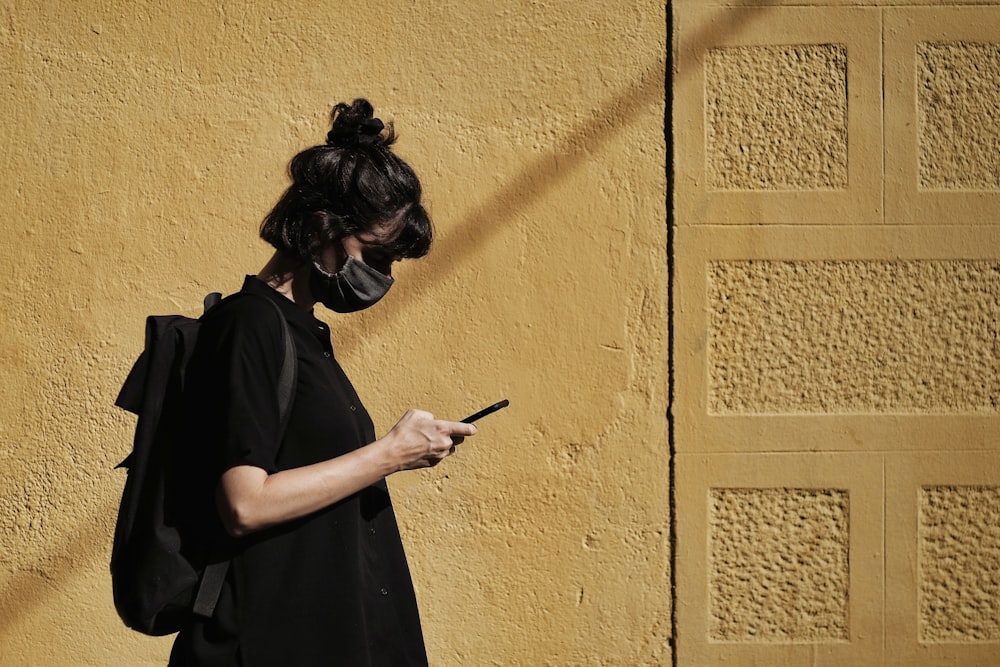 Frau in schwarzem Kleid mit Smartphone