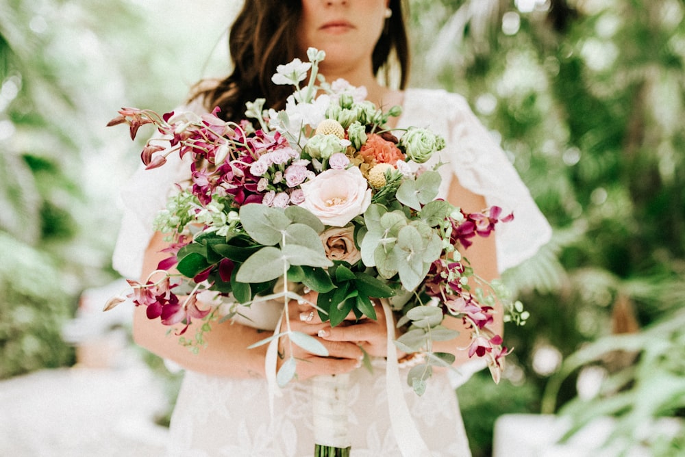 woman in white wedding dress holding bouquet of flowers