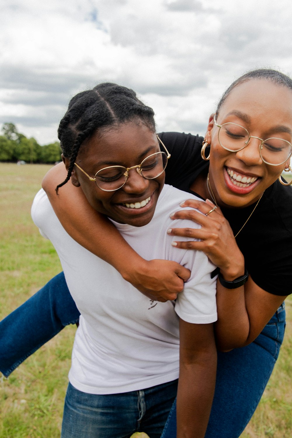 woman in white t-shirt hugging woman in blue sleeveless dress