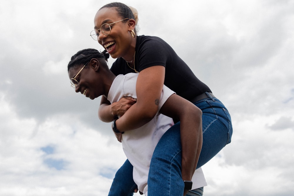 woman in white tshirt carrying woman in black shirt laughing