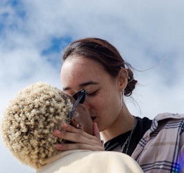 woman in white and woman in plaid shirt kissing