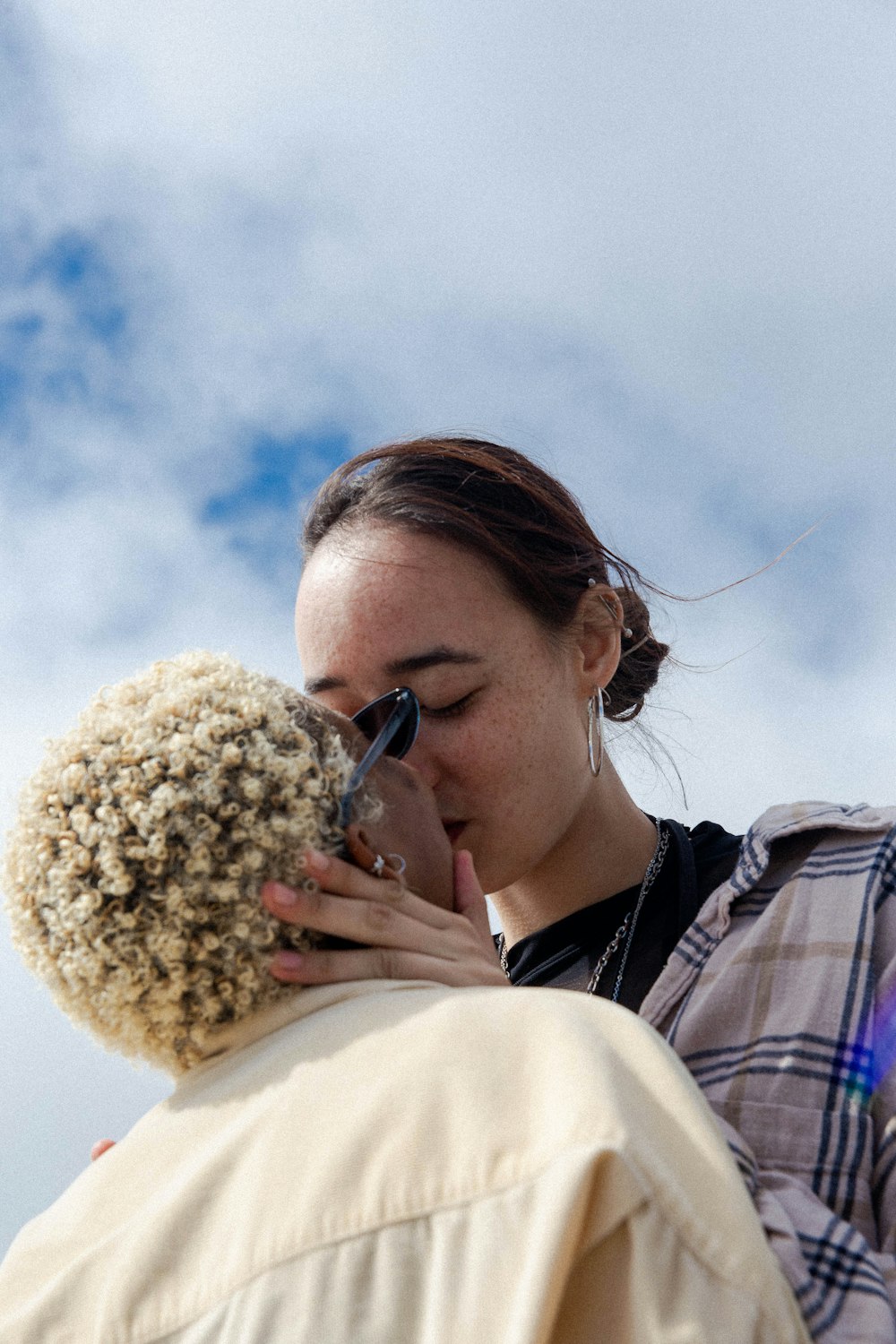 woman in white and woman in plaid shirt kissing