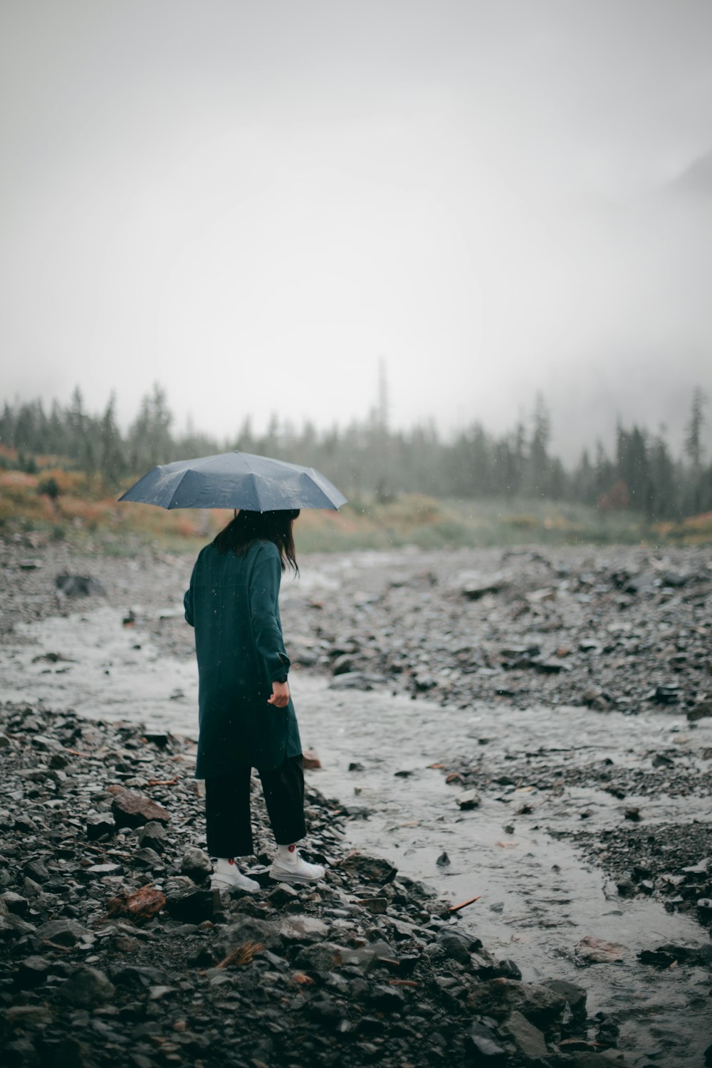 person in black jacket holding umbrella walking on dirt road during daytime