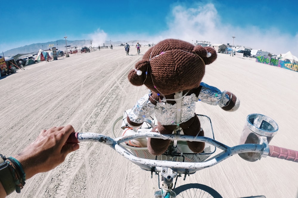 昼間、茶色の砂浜で自転車に乗る茶色のニット帽をかぶった男性