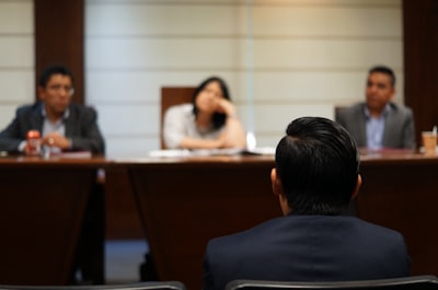 man in black shirt sitting beside woman in white shirt court google meet background