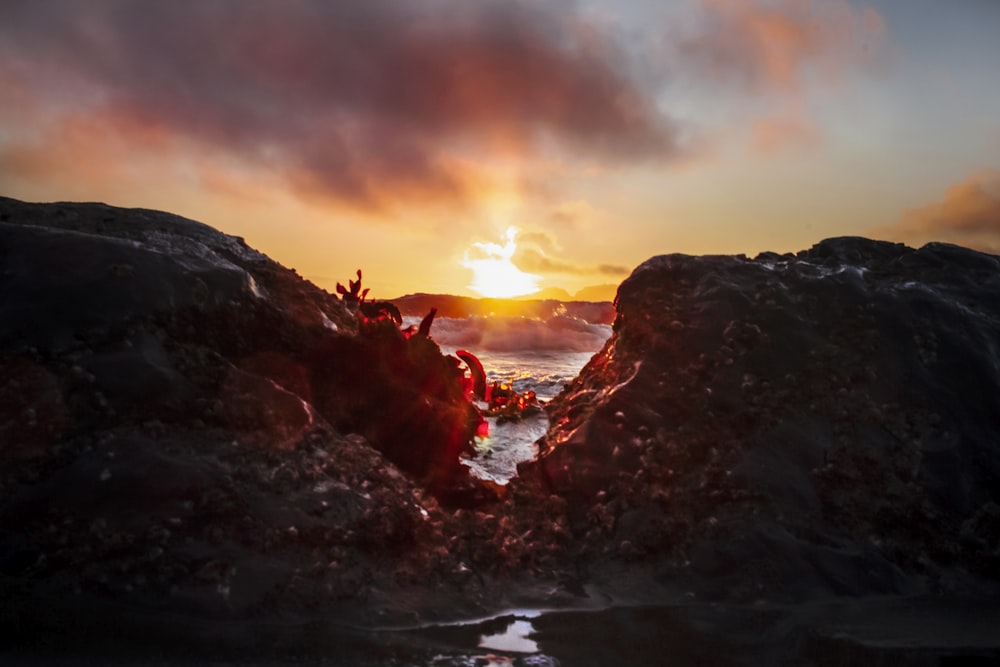 brown rock formation on body of water during sunset