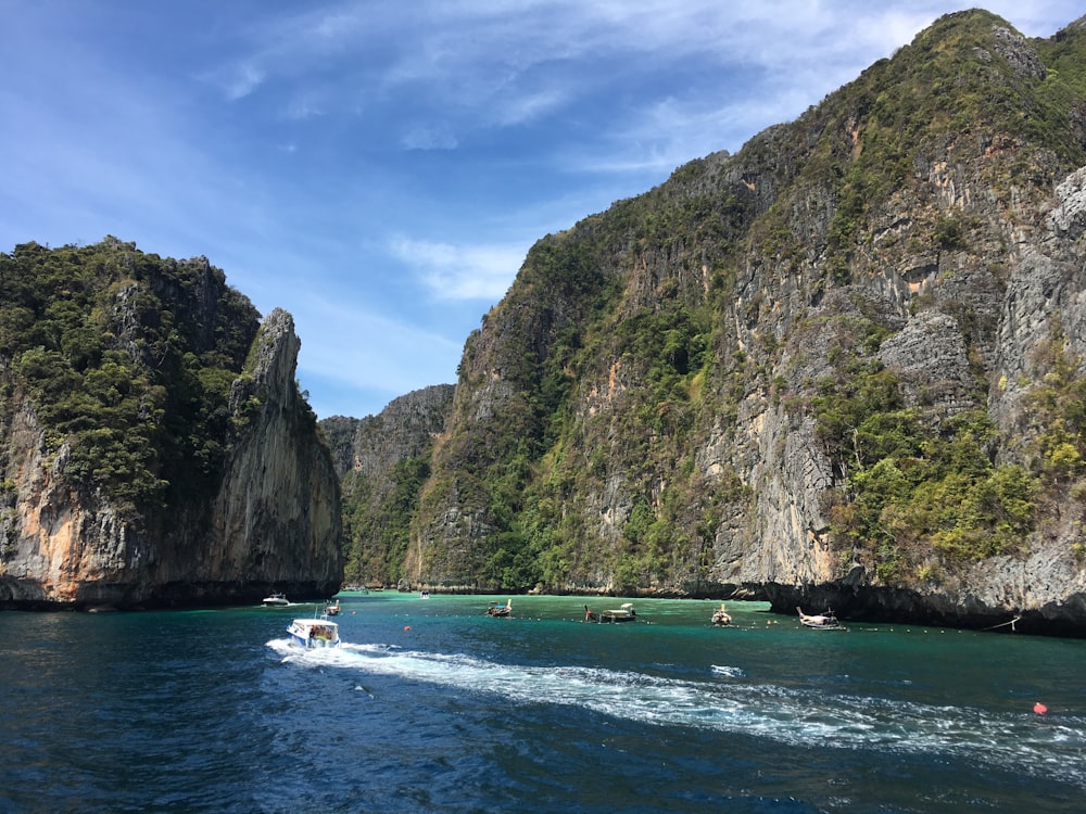 people riding on boat on sea near mountain during daytime