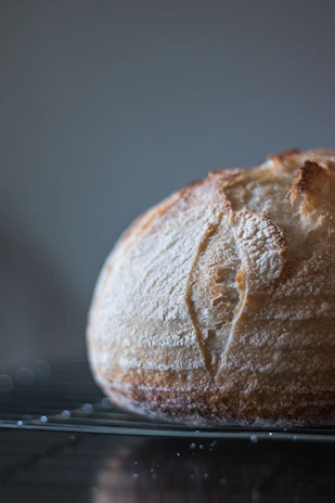 Close-up of golden crusted bread cooling on a rustic wooden rack in a cozy bakery.