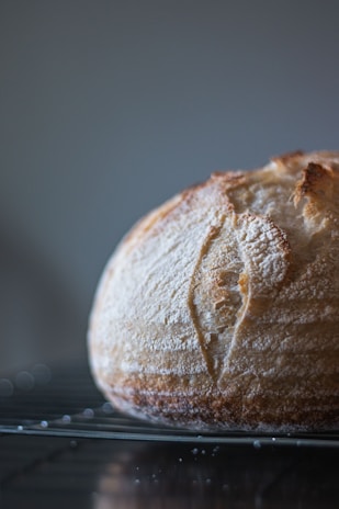 Warm bread loaves cooling on a wire rack, with soft natural light highlighting their crusty texture.