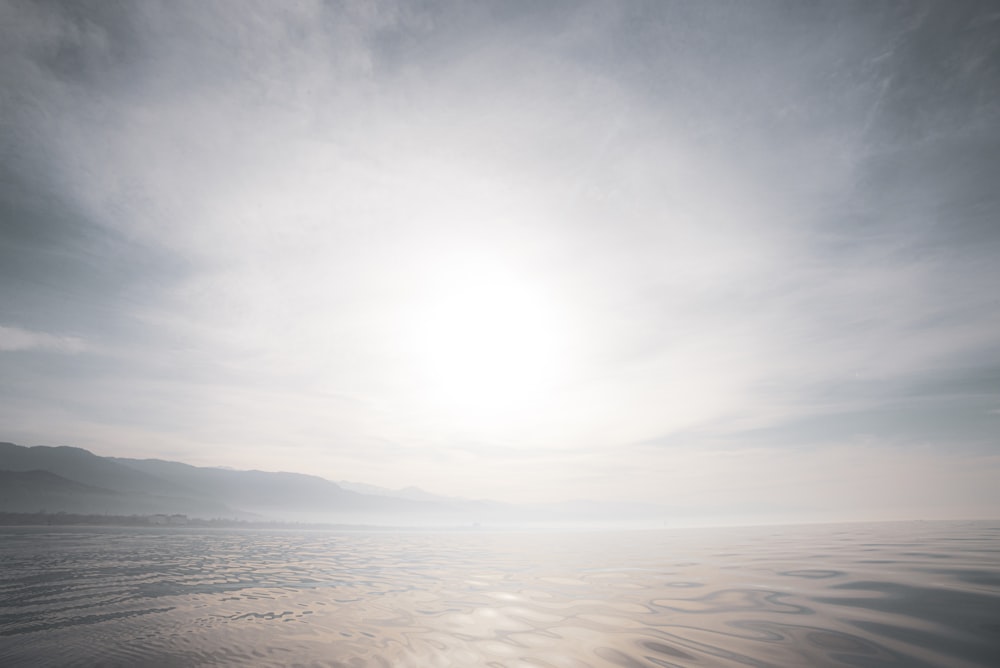 body of water under white clouds during daytime