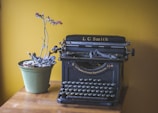black typewriter beside potted plant