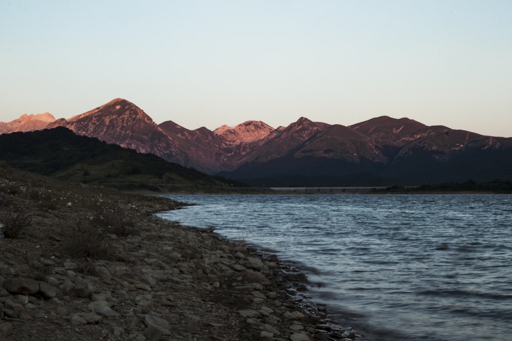 Montagna marrone vicino allo specchio d'acqua durante il giorno