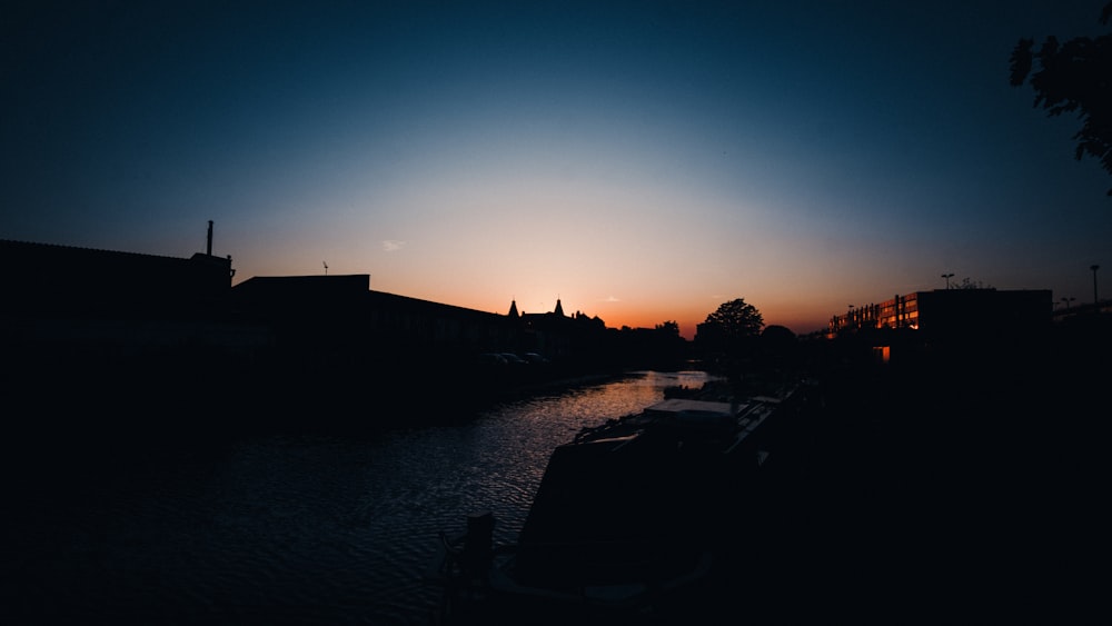 silhouette of buildings near body of water during sunset