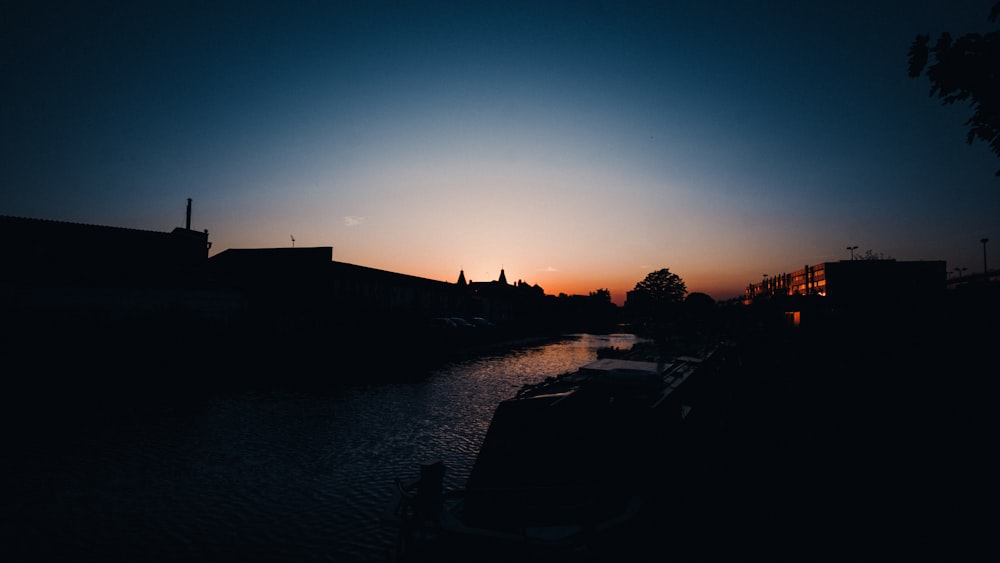 silhouette di edifici vicino allo specchio d'acqua durante il tramonto