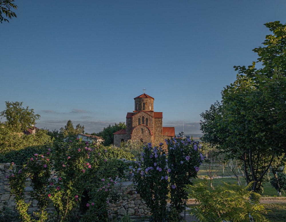 a church surrounded by trees and flowers on a sunny day