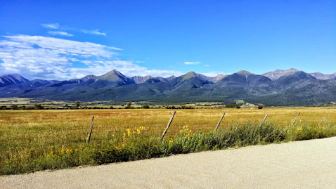 A warm Montana ranch landscape under open skies with a family discussing plans outdoors.