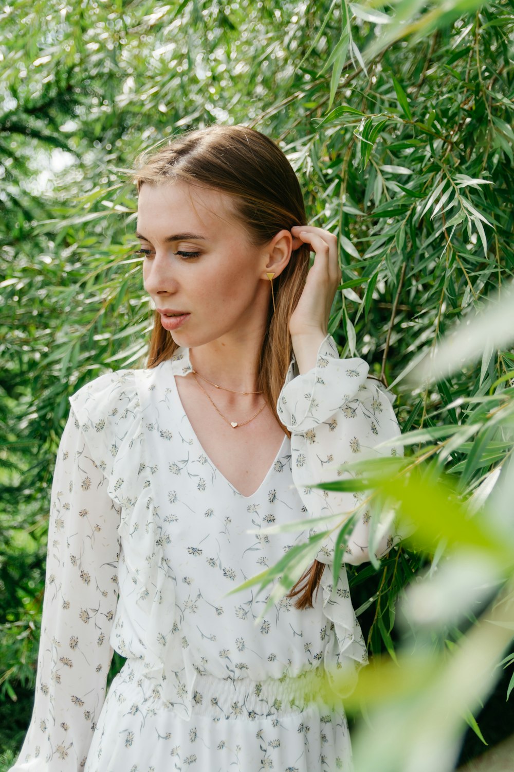 woman in white floral dress standing beside green plants during daytime