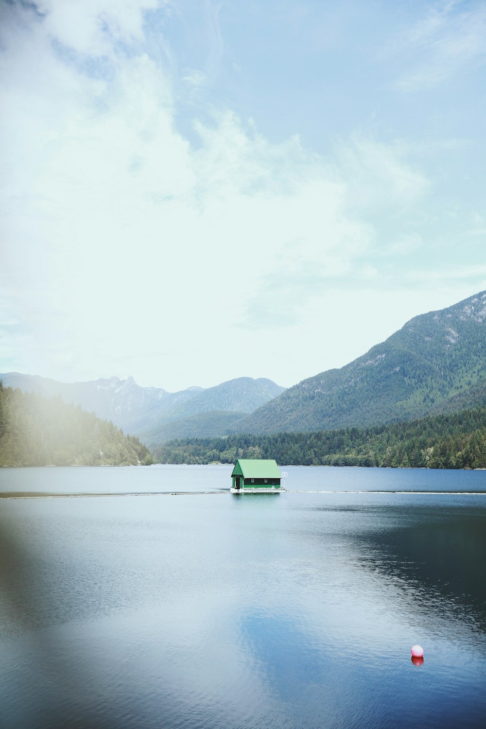 green boat on lake near green mountains during daytime