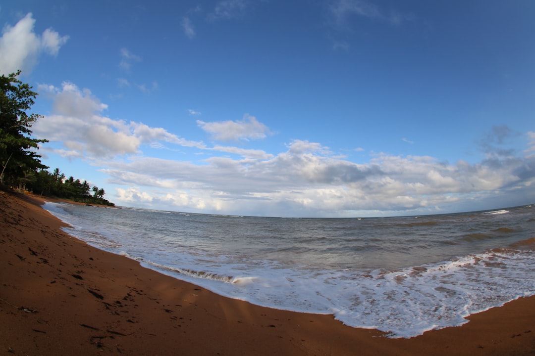 sea waves crashing on shore under blue sky and white clouds during daytime