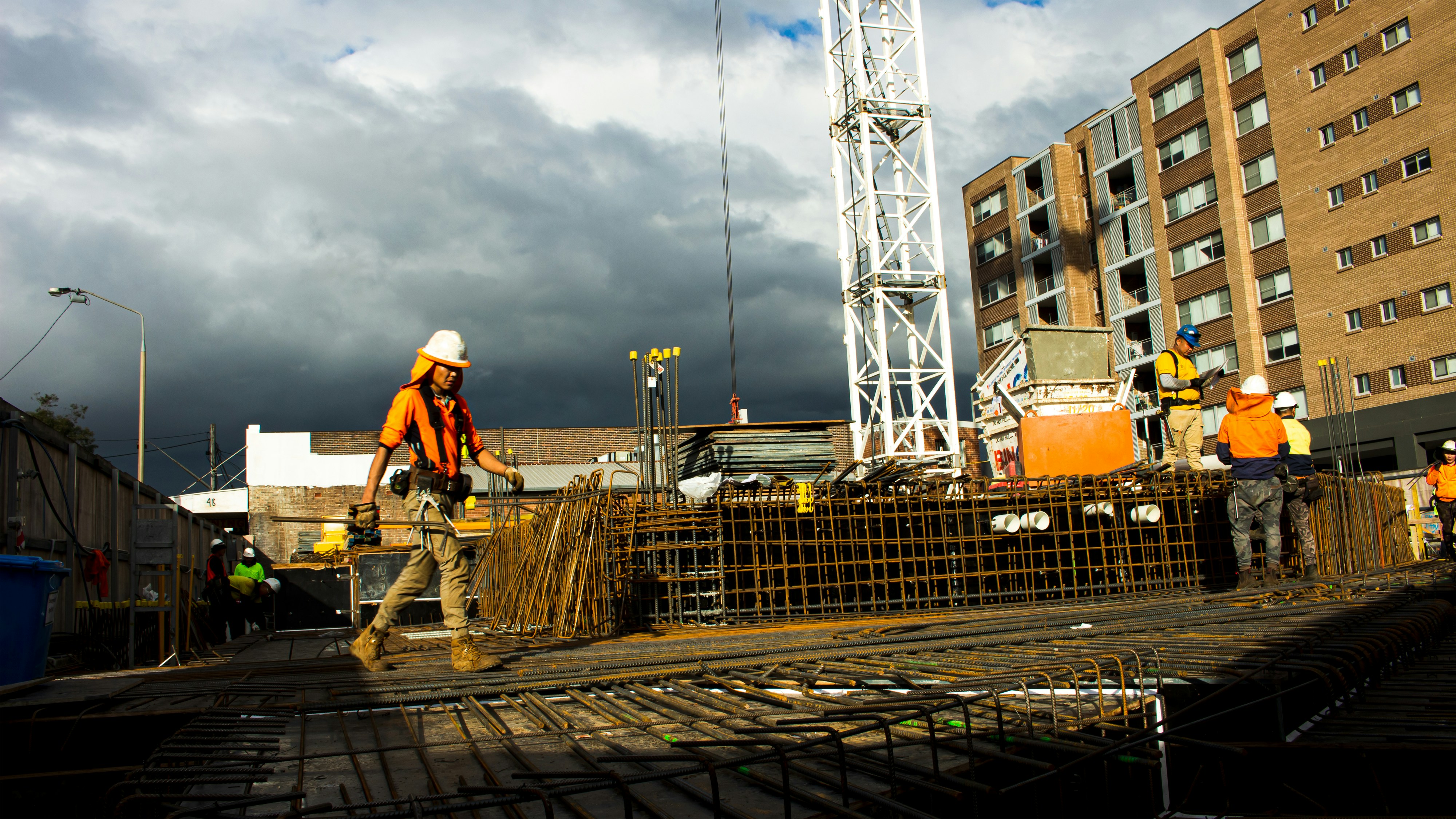SlavStroy construction team at work, sunny day, workers in orange safety vests, bright industrial setting